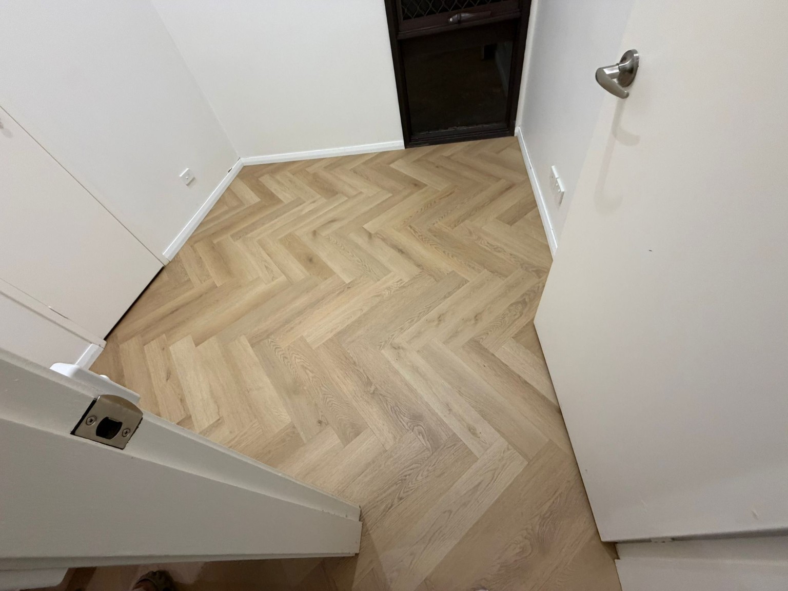 Light-oak herringbone timber flooring precisely fitted at an entry