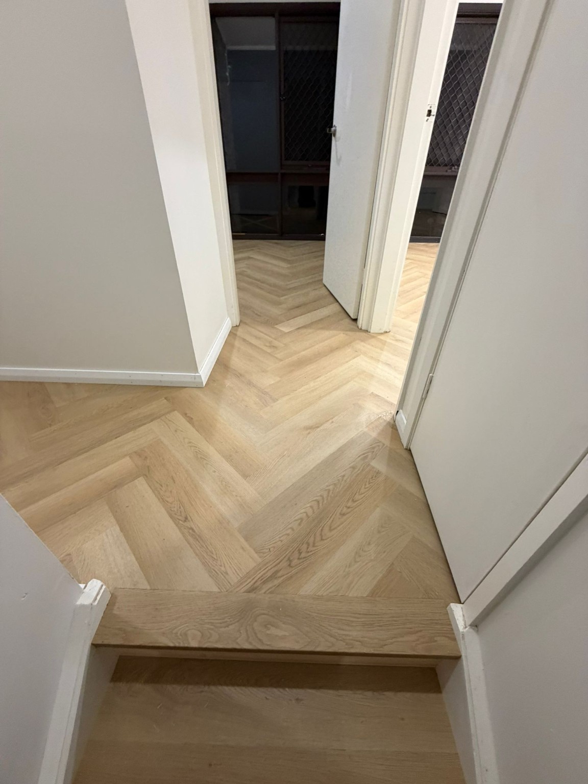 Completed light-oak herringbone timber flooring through a hallway and landing